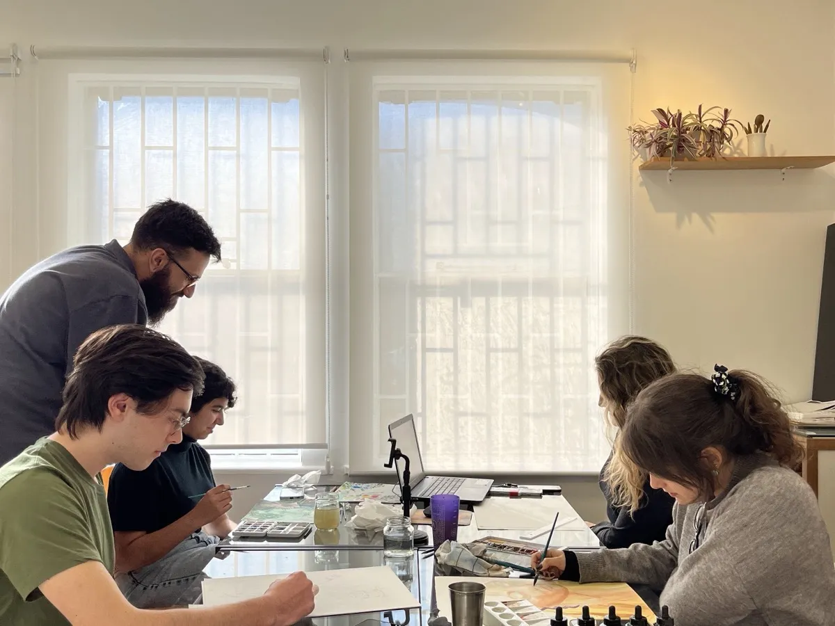 Professor da Desenhe orientando um grupo em volta da mesa de trabalho