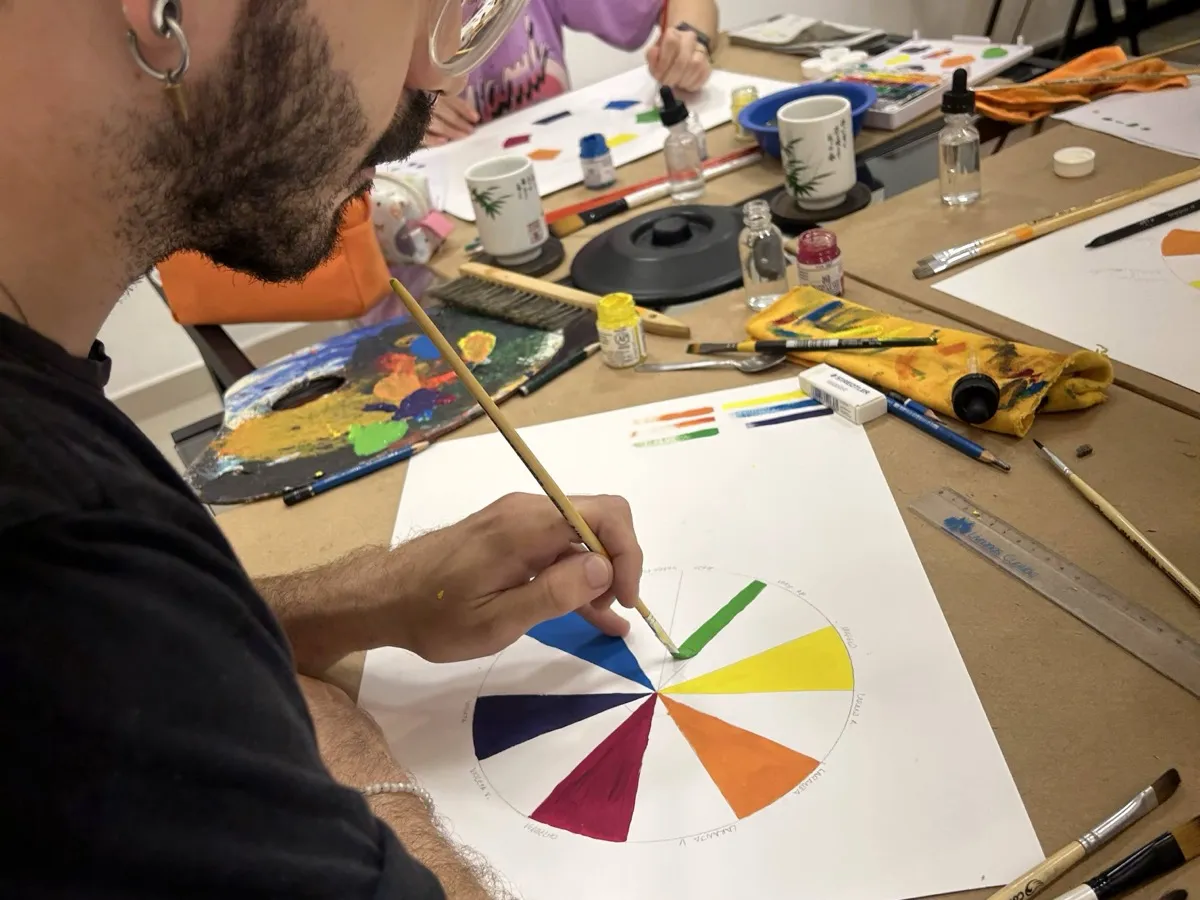 Aluno pintando um círculo cromático com as cores primárias